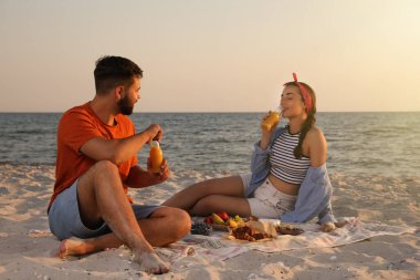 Deniz kenarındaki kumsalda piknik yapan sevimli bir çift.