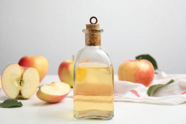 Doğal elma sirkesi ve beyaz masada taze meyveler.