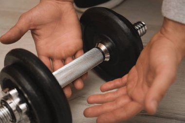 Atletin biri dambılı içeri alıyor, yakın plan. Eldeki nasırlardan muzdarip.