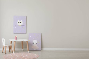 Çocuk odasının içinde masa, güzel tablolar ve boş duvar var. Tasarım için boşluk