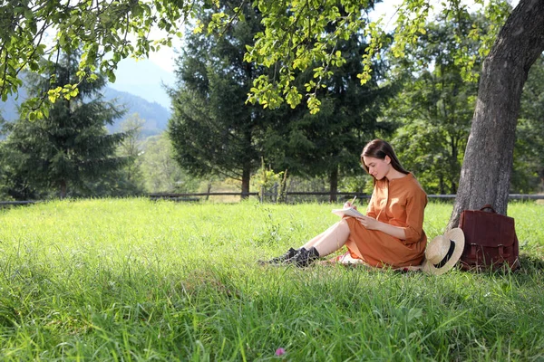 Krásná Mladá Žena Kresba Tužkou Notepadu Blízkosti Stromu Zelené Trávě — Stock fotografie