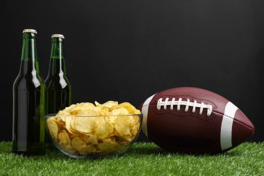 Amerikan futbol topu patates cipsi ve yeşil çimlerin üzerinde bira