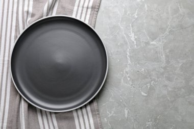 Açık gri mermer masa üzerinde yeni siyah tabak ve masa örtüsü, üst manzara. Metin için boşluk