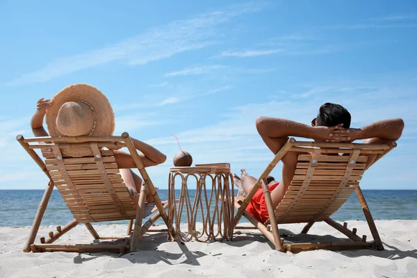 在热带海滩的木制日光浴床上休息的夫妻 — 图库照片