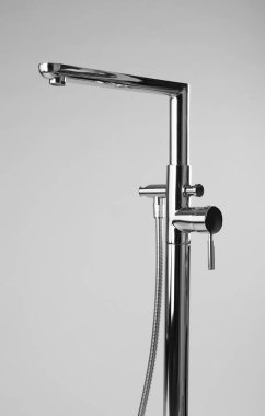 Gri arka planda el banyosu olan modern banyo musluğu.