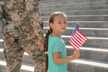 Asker ve açık havada Amerikan bayrağı taşıyan küçük kızı. ABD 'de Gaziler Günü
