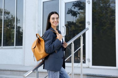 Açık hava binasının yakınında şık bir sırt çantası olan güzel bir genç kadın.
