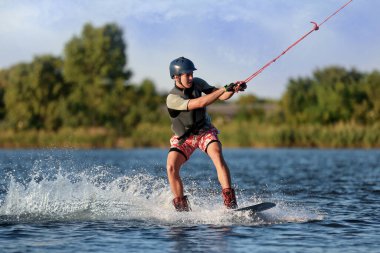 Genç çocuk nehirde wakeboard yapıyor. Aşırı su sporu