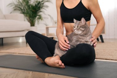 Evde yoga yaparken kedisini okşayan kadın, yakın çekim.