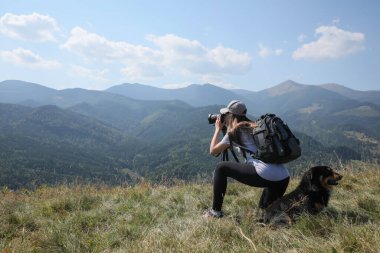 Dağlarda resim çeken köpekli profesyonel fotoğrafçı. Metin için boşluk