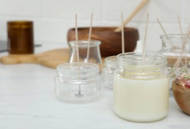 Beyaz masada balmumu ve fitil olan cam kavanoz, mesaj için yer. Ev yapımı mum yapıyorum.