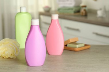 Banyodaki ahşap masadaki duş jeli, sünger ve sabunluklar.