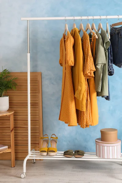 Cremalheira Com Roupas Elegantes Perto Parede Azul Clara Dentro Casa — Fotografia de Stock