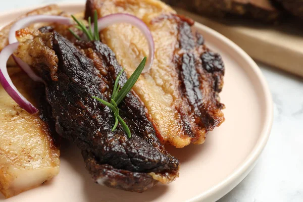 白テーブルの上にローズマリーと玉ねぎとおいしい揚げ豚肉のラード クローズアップ — ストック写真