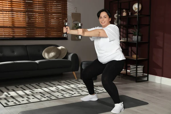 Kilolu Olgun Bir Kadın Evde Dambıllarla Egzersiz Yapıyor — Stok fotoğraf