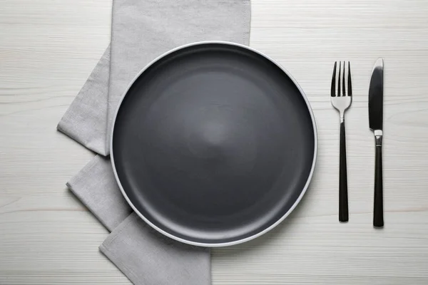 白色木制桌子上新的深色盘子和餐具 — 图库照片