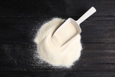 Jelatin tozu yığını ve kepçeyle siyah ahşap masa, üst manzara.