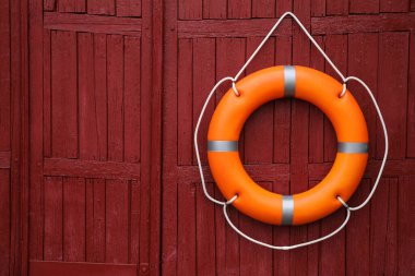 Kırmızı ahşap duvarda asılı turuncu yaşam şamandırası, metin için boşluk