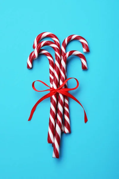 Sweet Christmas Snoepgoed Stokken Met Rode Strik Lichtblauwe Achtergrond Bovenaanzicht — Stockfoto