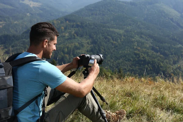 三脚の上で現代的なカメラで山の風景の写真を撮る男屋外 — ストック写真