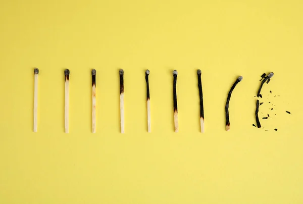 Different stages of burnt matches on yellow  background, flat lay
