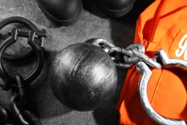 Zincirli mahkum topu ve hapishane kıyafetleri gri masada, düz yatıyordu.