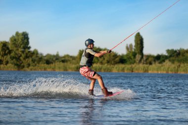 Genç çocuk nehirde wakeboard yapıyor. Aşırı su sporu
