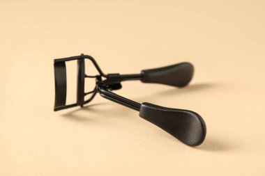 Bej arka planda kirpik bigudisi, yakın plan. Makyaj aracı