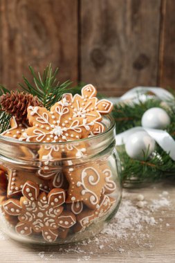 Cam kavanozda lezzetli Noel kurabiyeleri ve bej ahşap masada şenlikli bir dekor.