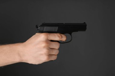 Koyu arkaplanda silahı hedef alan adam, yakın plan.
