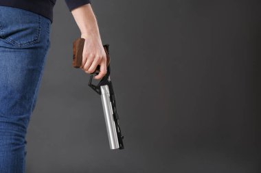 Atış sporu. Karanlık arka planda standart tabanca tutan adam, yakın plan. Metin için boşluk