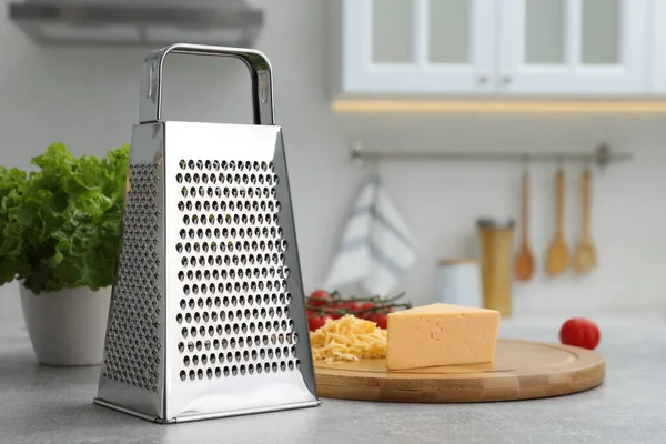 Grater and cheese on table in kitchen. Space for text