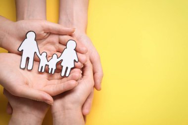 Sarı arka planda kağıt aile kesimi olan insanlar var. Metin için boşluk