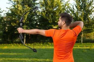 Ok ve yaylı adam parkta okçuluk yapıyor.