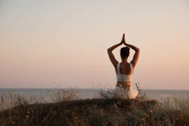 Deniz kenarında meditasyon yapan bir kadın. Metin için boşluk
