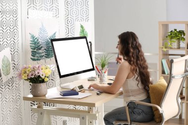 Masadaki bilgisayarda çalışan genç bir kadın.