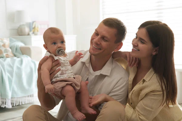 一对快乐的夫妇和他们可爱的小宝宝在家里带着奶嘴 — 图库照片