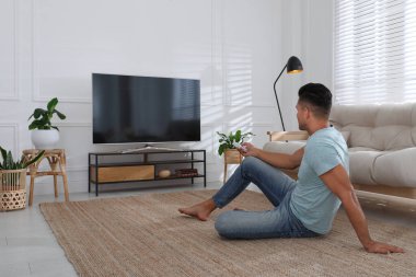 Evde televizyon izleyen bir adam. Oturma odasının içinde televizyon var.