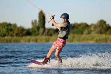 Genç çocuk nehirde wakeboard yapıyor. Aşırı su sporu
