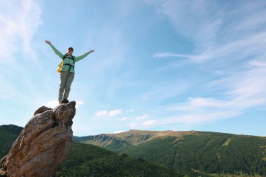Sırt çantalı genç bir kadın dağlardaki kayalık zirvede. Metin için boşluk