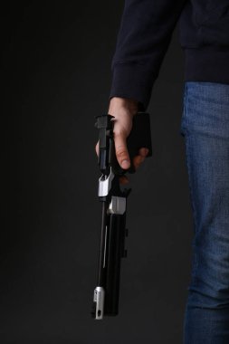 Atış sporu. Karanlık arka planda standart tabanca tutan adam, yakın plan.