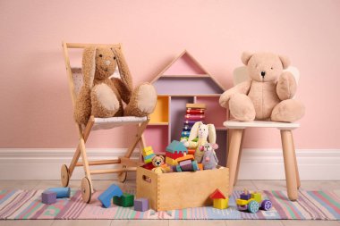 Pembe duvarın yanında yerde farklı oyuncaklar var.