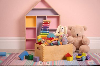 Pembe duvarın yanında yerde farklı oyuncaklar var.