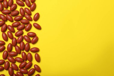 Sarı arkaplanda bir sürü hap, metin için yeri olan düz bir yatak.