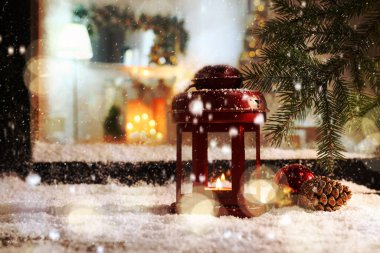 Dışarıda Noel feneriyle pencere eşiğine kar yağıyor. 