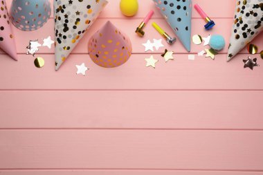 Düz kompozisyon, parti şapkaları ve pembe ahşap arka plandaki diğer şenlikli eşyalar. Metin için boşluk