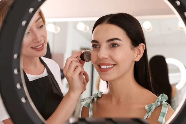 Profesjonalny Makijaż Artysta Pracuje Piękną Młodą Kobietą Salonie Widok Przez — Zdjęcie stockowe