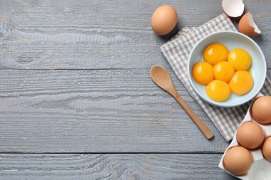 Gri ahşap masa üzerinde çiğ yumurta ve kase, düz. Metin için boşluk