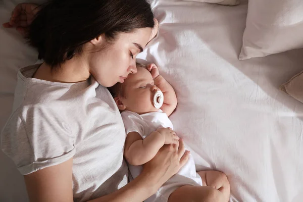 Νεαρή Μητέρα Ξεκουράζεται Κοντά Στο Κοιμισμένο Μωρό Της Στο Κρεβάτι — Φωτογραφία Αρχείου