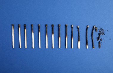 Mavi arka planda yanmış kibritlerin farklı aşamaları, düz yatış